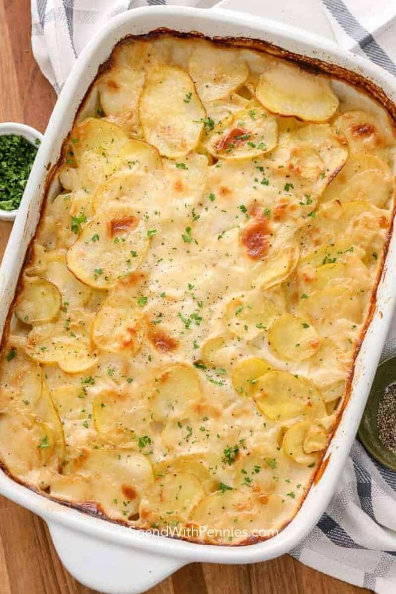 A 9x13 pan of baked scalloped potatoes topped with parsley