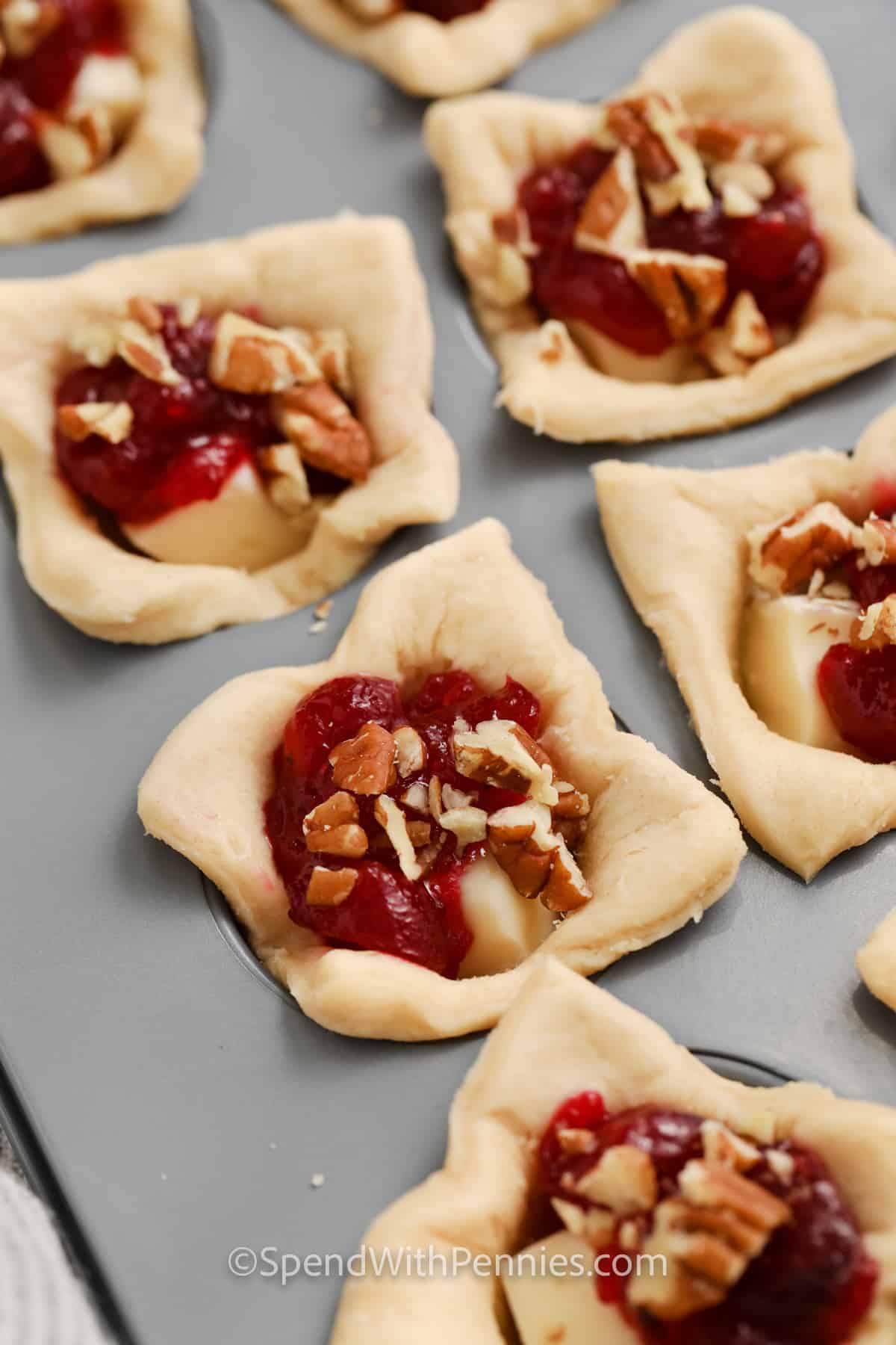 adding pecans and cranberry sauce to Cranberry Brie Bites