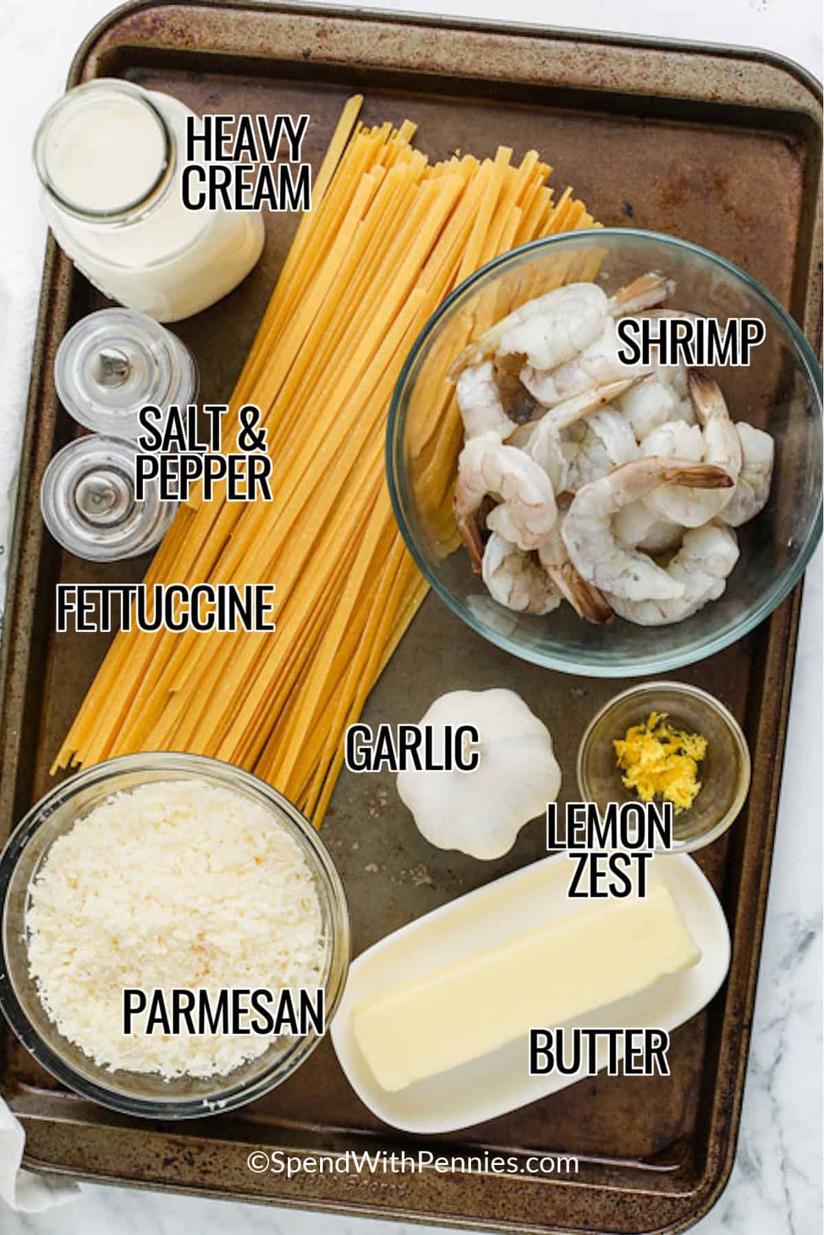 Ingredients to make Shrimp Alfredo labeled: heavy cream, shrimp, salt & pepper, fettuccini, garlic, lemon zest, parmesan, and butter.