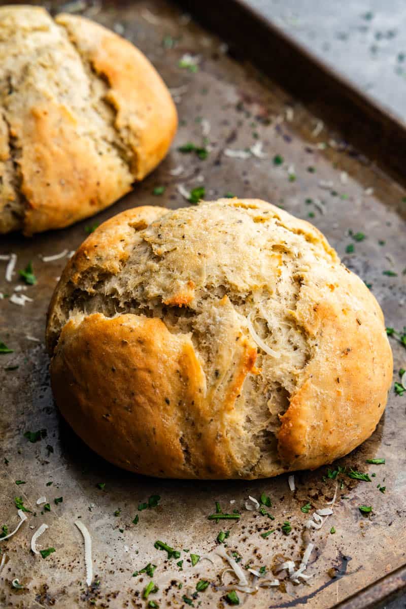 Two loaves of garlic parmesan herb bread on a baking sheet.