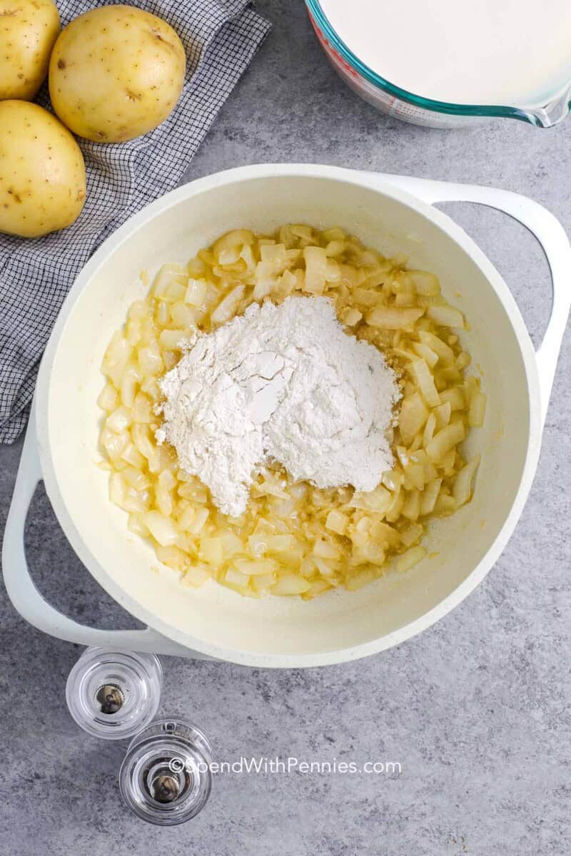 Flour on top of cooked onions in a small pot for making scalloped potatoes sauce