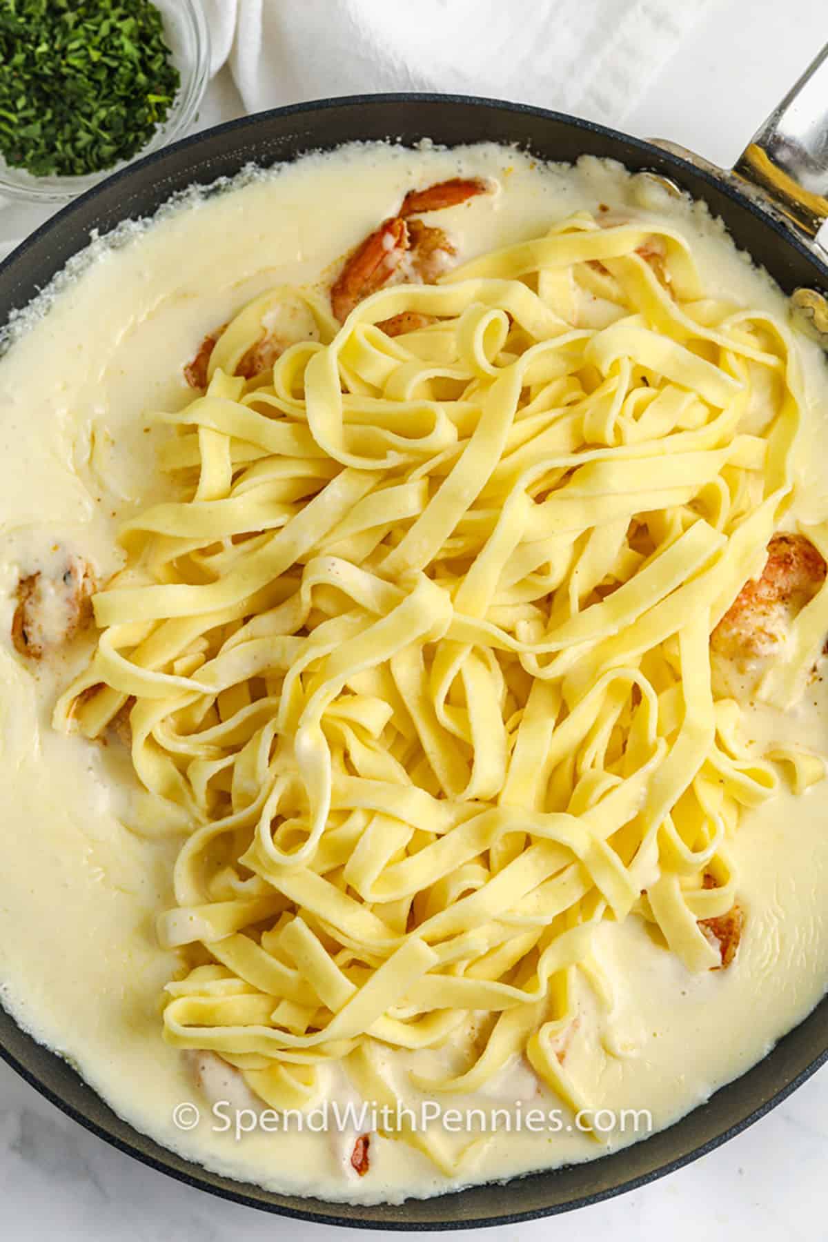 adding pasta to pan to make Shrimp Alfredo