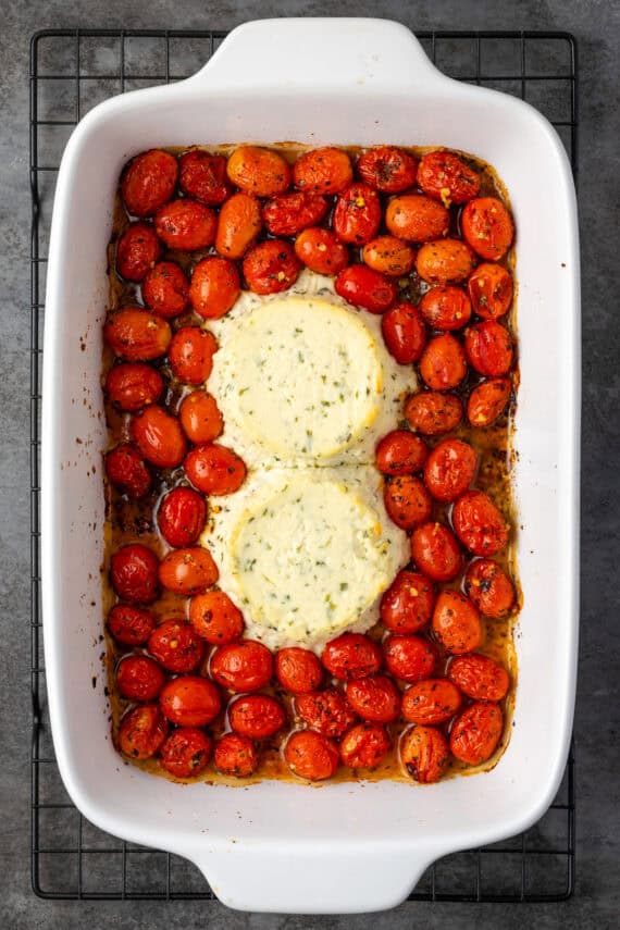 Two rounds of baked Boursin cheese and tomatoes in a casserole dish.