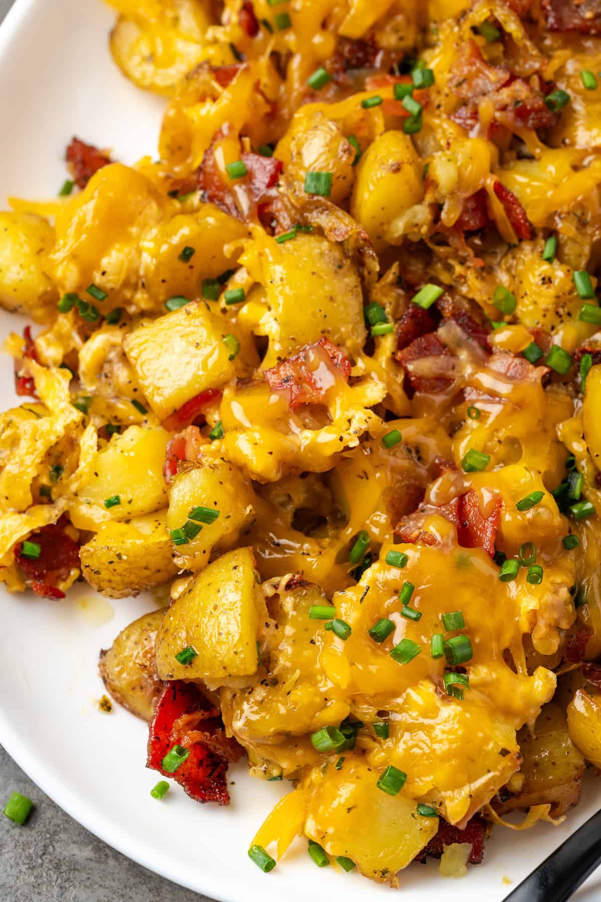 Close up of cheesy ranch potatoes on a white platter.