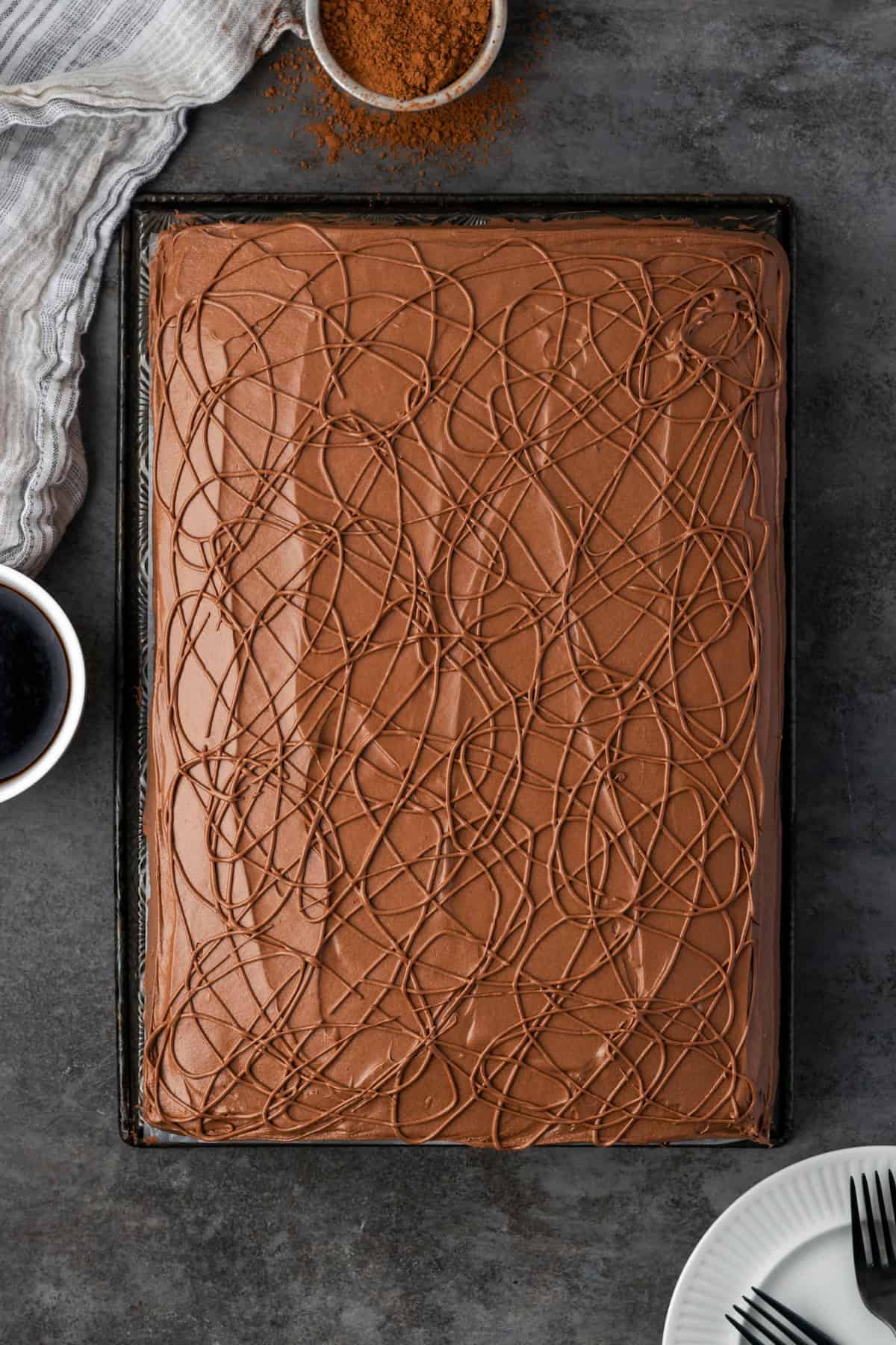 Overhead view of a frosted fudge cake swirled with icing in large cake pan.