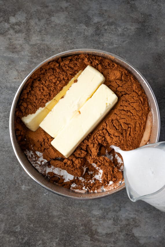 Milk being poured into a bowl with the other fudge frosting ingredients.