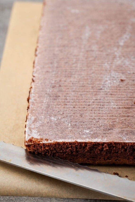 A chocolate sheet cake layer covered with parchment paper.