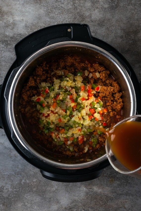 Additional beef broth is poured over sauteed diced veggies aded to ground beef in the instant pot.