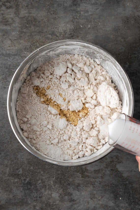 Milk added to frosting ingredients in a mixing bowl.