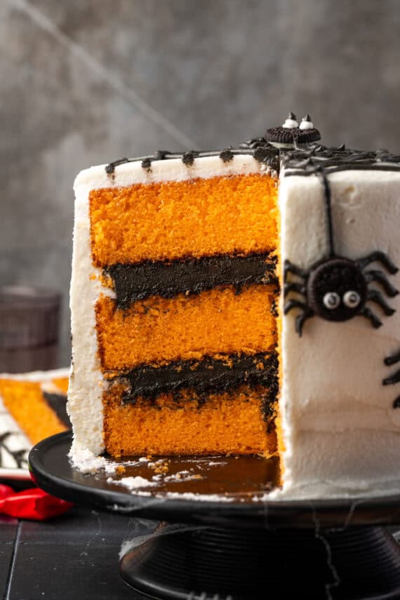 Side view of a spider cake with a large slice cut out, revealing the orange cake layers inside.