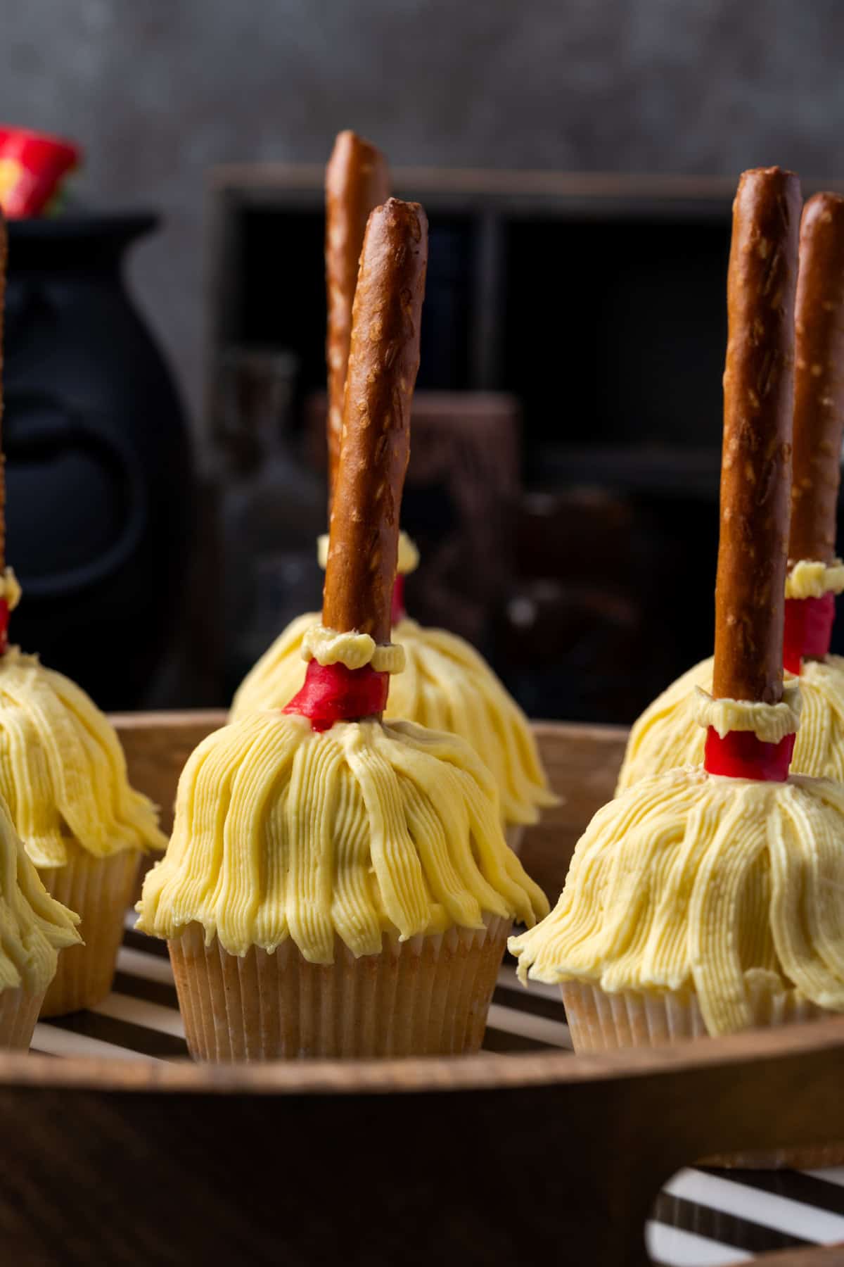 Side view of a witch's broom cupcakes on a wooden tray.